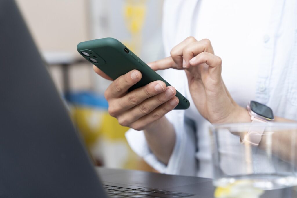 Mulher com celular na mão usando o WhatsApp